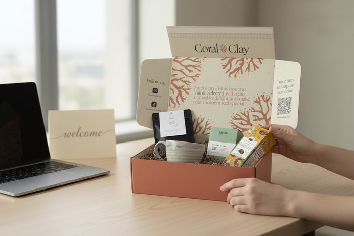 Unboxing of a Coral & Clay employee gift  box on a desk with a laptop and 'welcome' card.