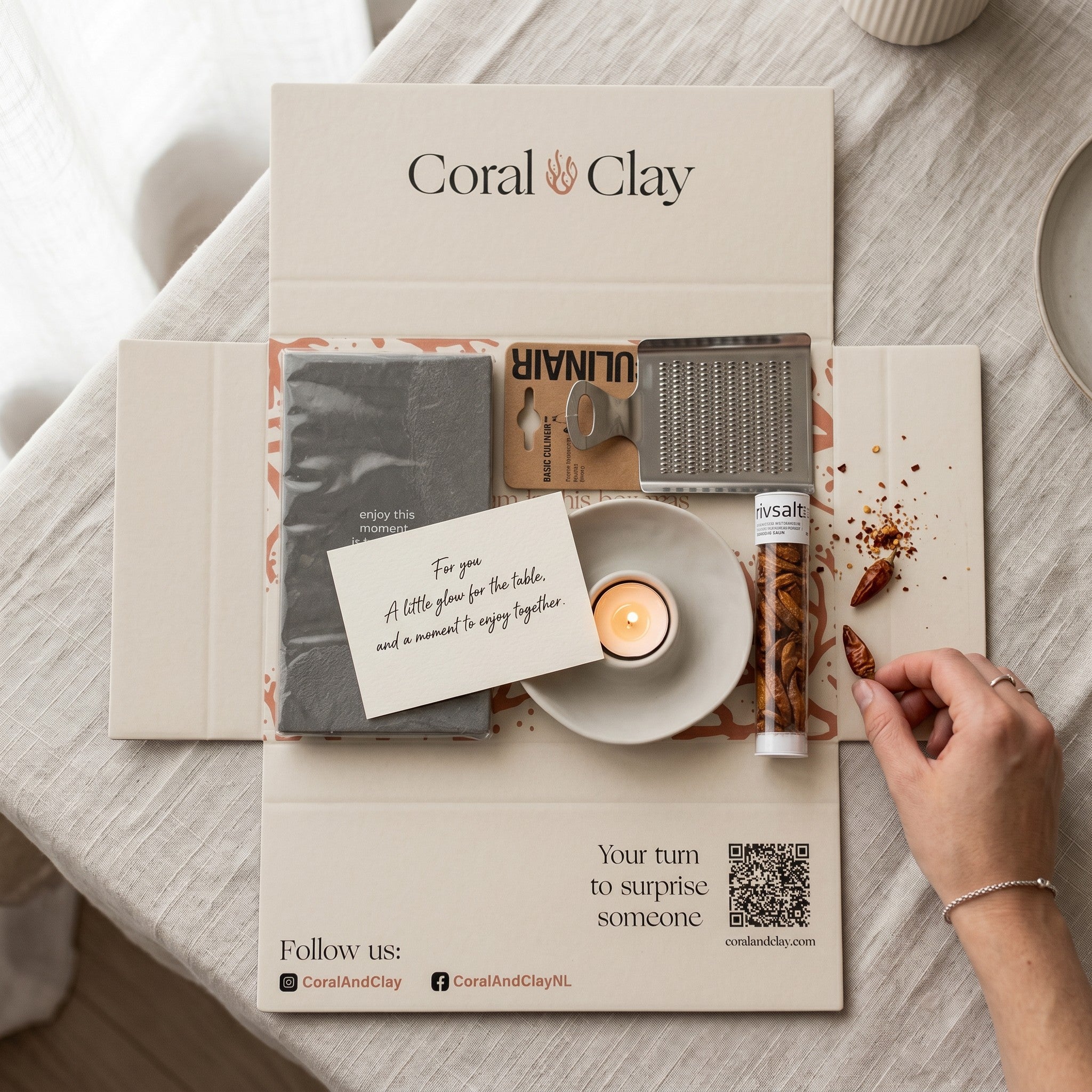 Coral & Clay product packaging with a hand holding a small item on a light wooden surface.