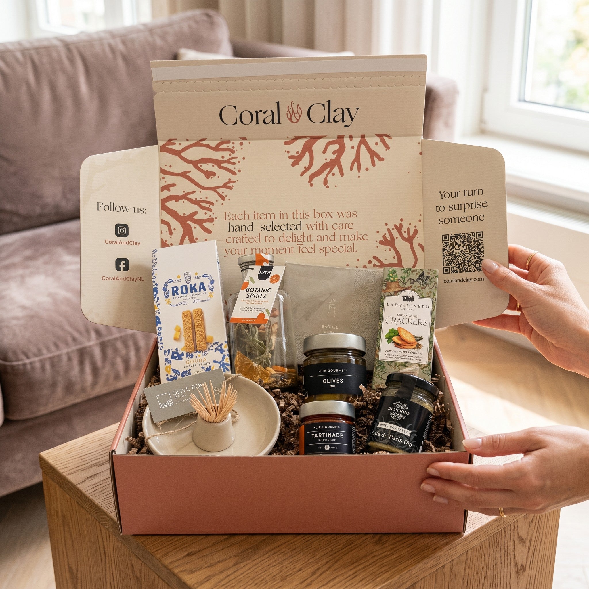 Gift box with various items on a wooden table, featuring the brand 'Coral Clay'.