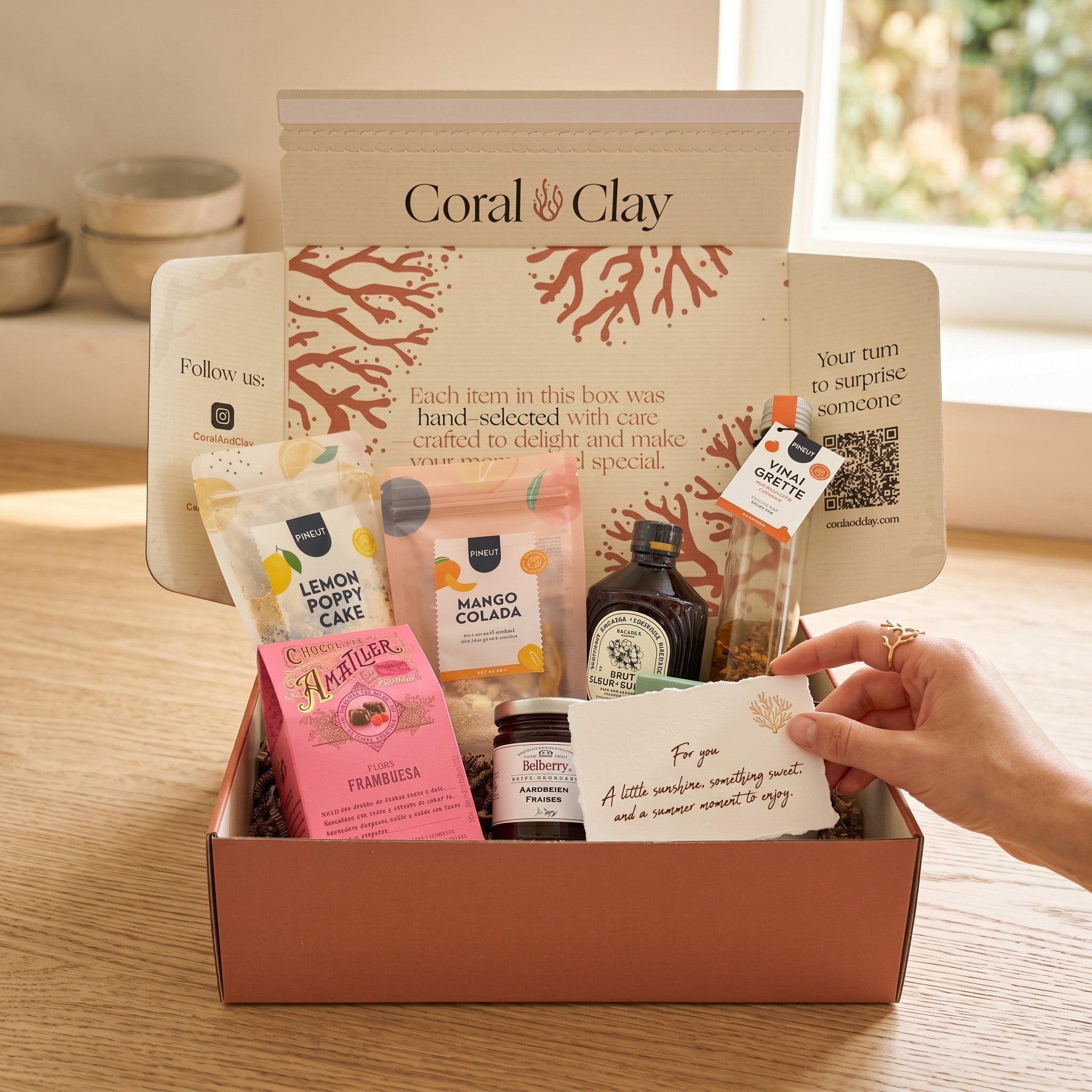 Coral & Clay Summer Feeling Signature Gift lifestyle photo – wooden board scene with Mango Colada drink mix, elderflower syrup, lemon & poppy cake mix, strawberry confiture, raspberry pralines, Spanish pepper & orange vinaigrette, and scented candle.