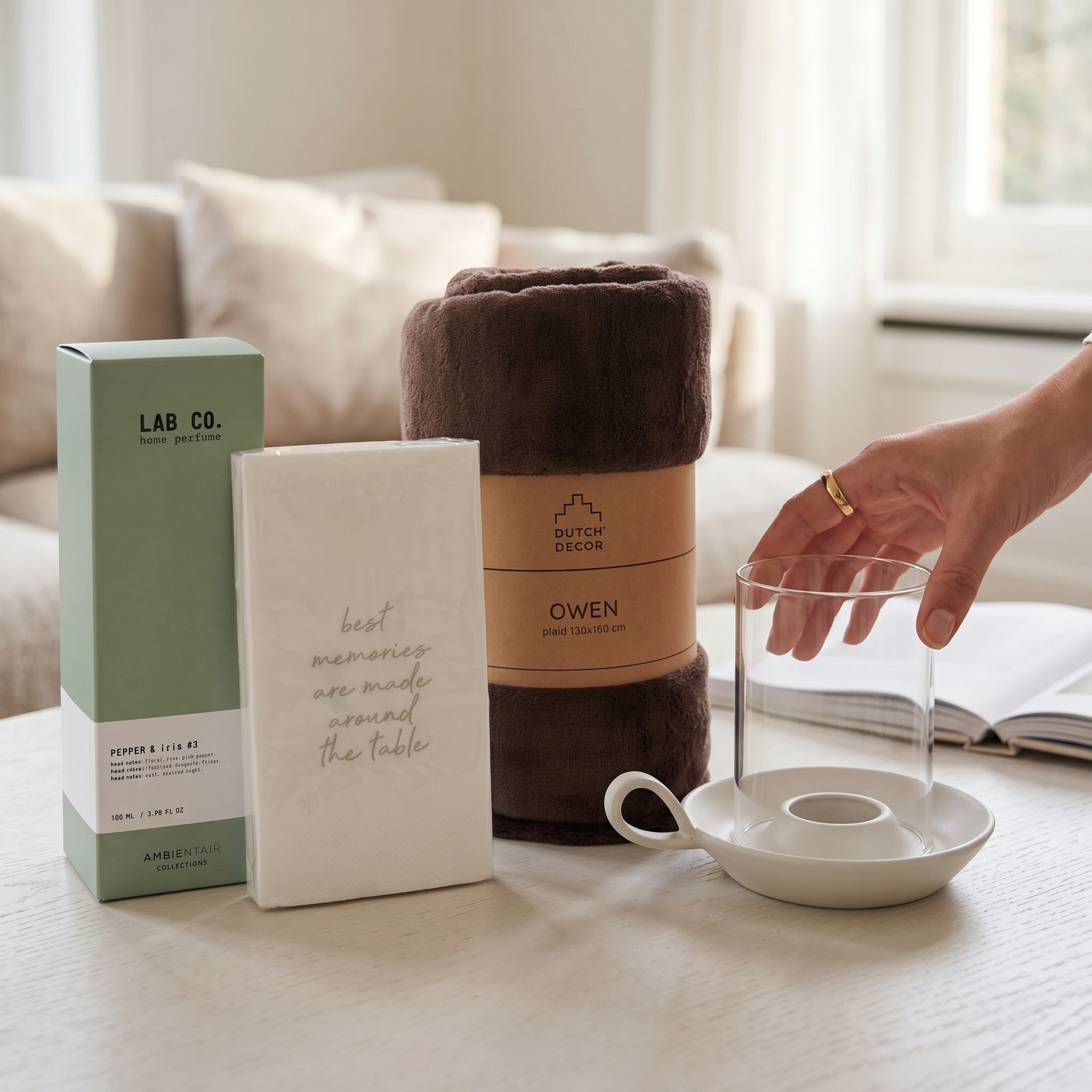Product display with a blanket, box, and ceramic items on a table.