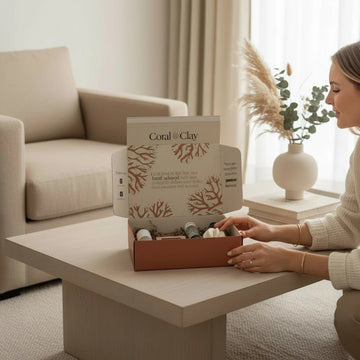 Woman opening a box of Coral & Clay products in a living room.