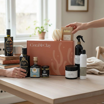 Coral & Clay giftbox surrounded by product set on a wooden table with a hand reaching for a box.