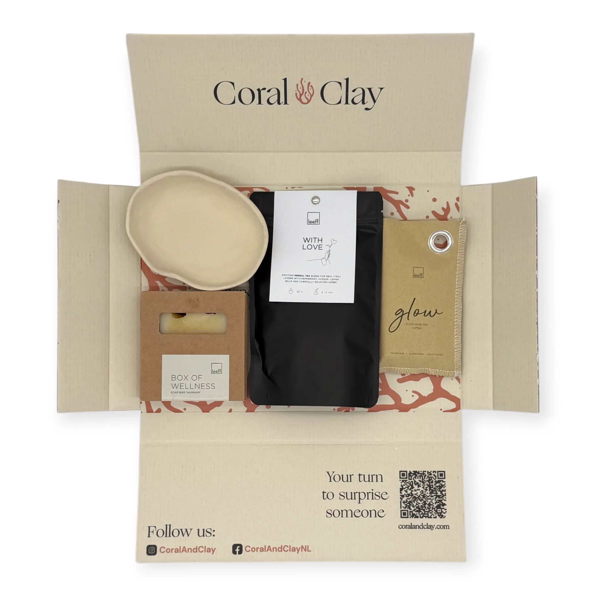Top-down view of the Coral & Clay Body & Mind Letterbox Gift opened to reveal the Box of Wellness soap bar, With Love herbal tea, Glow sachet, and ceramic dish inside the printed mailer box.