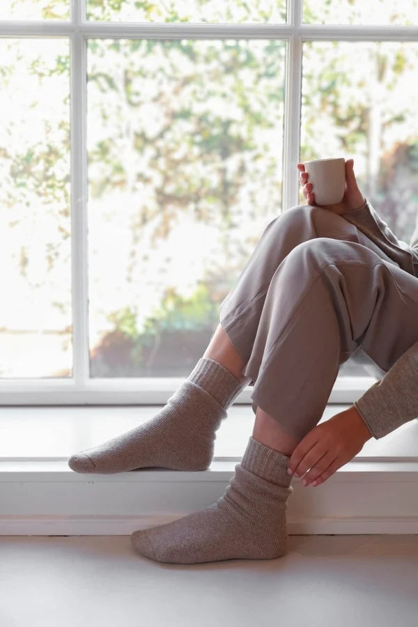 Leeff Warm Hug wool socks in sand worn while relaxing indoors.