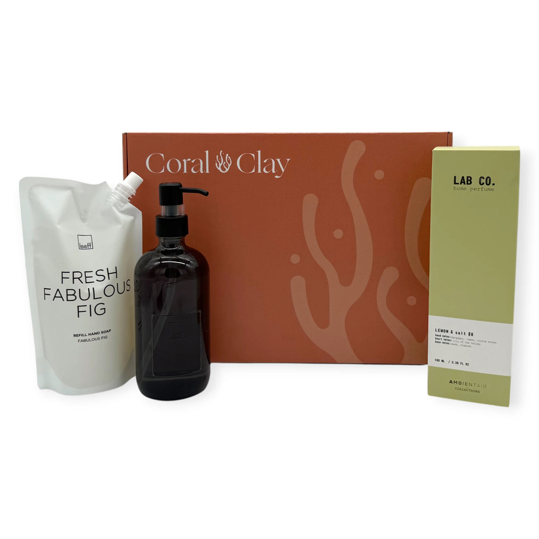Signature Hands & Home gift set arranged in front of a Coral & Clay signature box, showing Fresh Fabulous Fig hand soap refill, black glass soap dispenser, and Lab Co Lemon & Salt home perfume.