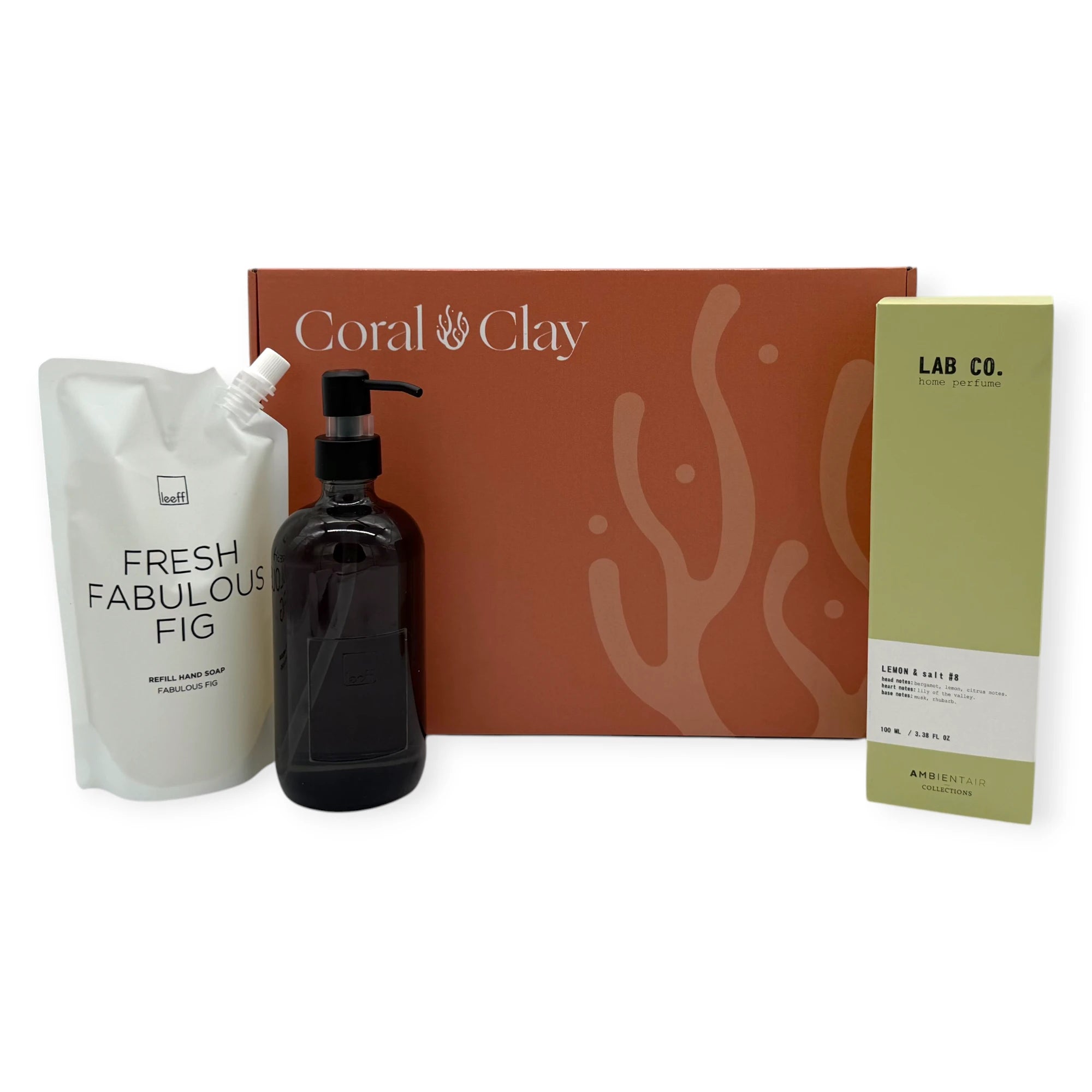 Signature Hands & Home gift set arranged in front of a Coral & Clay signature box, showing Fresh Fabulous Fig hand soap refill, black glass soap dispenser, and Lab Co Lemon & Salt home perfume.
