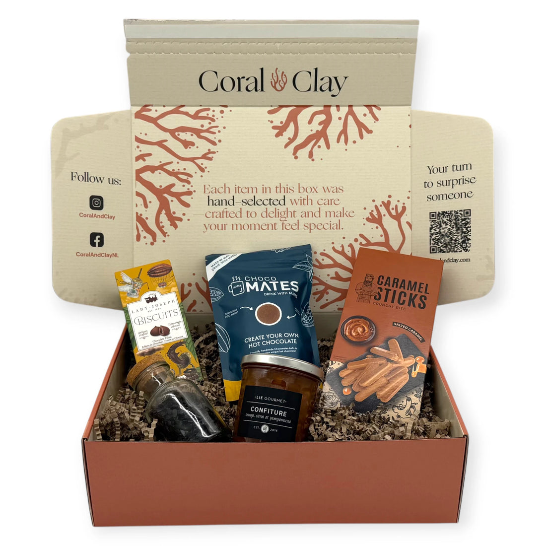 The Sunday Afternoon Signature Gift displayed in front of a Coral & Clay gift box, featuring caramel sticks, hot chocolate mix, chocolate-filled biscuits, fruit confiture, and a small bottle of chocolate flakes arranged neatly for a hero product shot.