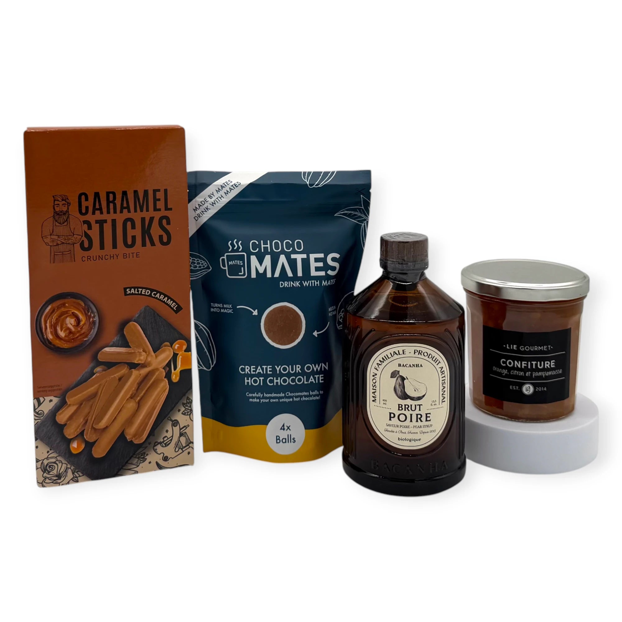 Sweet Indulgence Signature Gift contents displayed upright, featuring Choco Mates hot chocolate mix, caramel sticks, Maison Familiale Brut Poire syrup, and LIE Gourmet mango–lemon–passionfruit confiture.