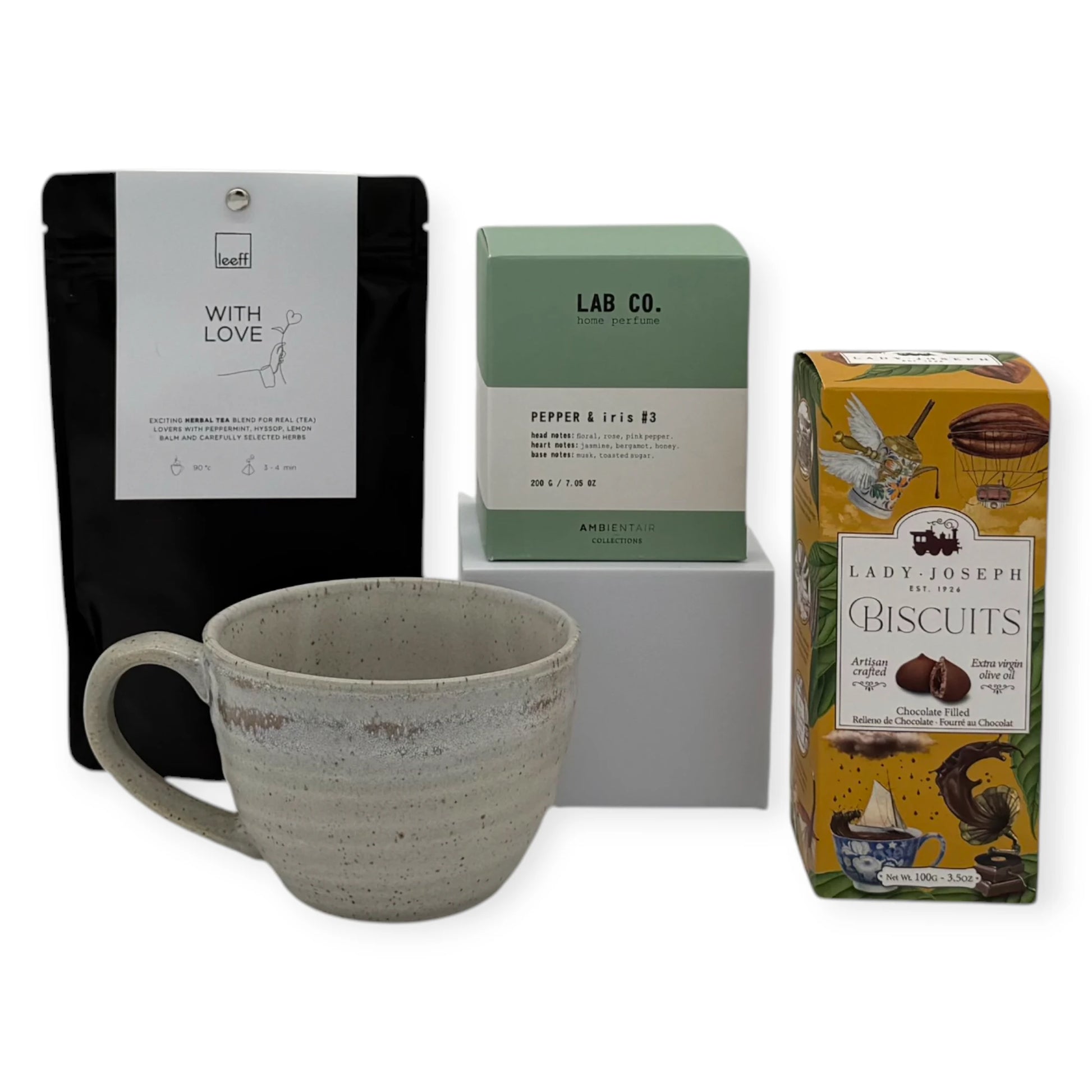 Tea Time Signature Gift contents arranged together, featuring Leeff With Love herbal tea, Lab Co. Pepper & Iris home perfume, Lady Joseph chocolate-filled biscuits, and a handcrafted ceramic mug.