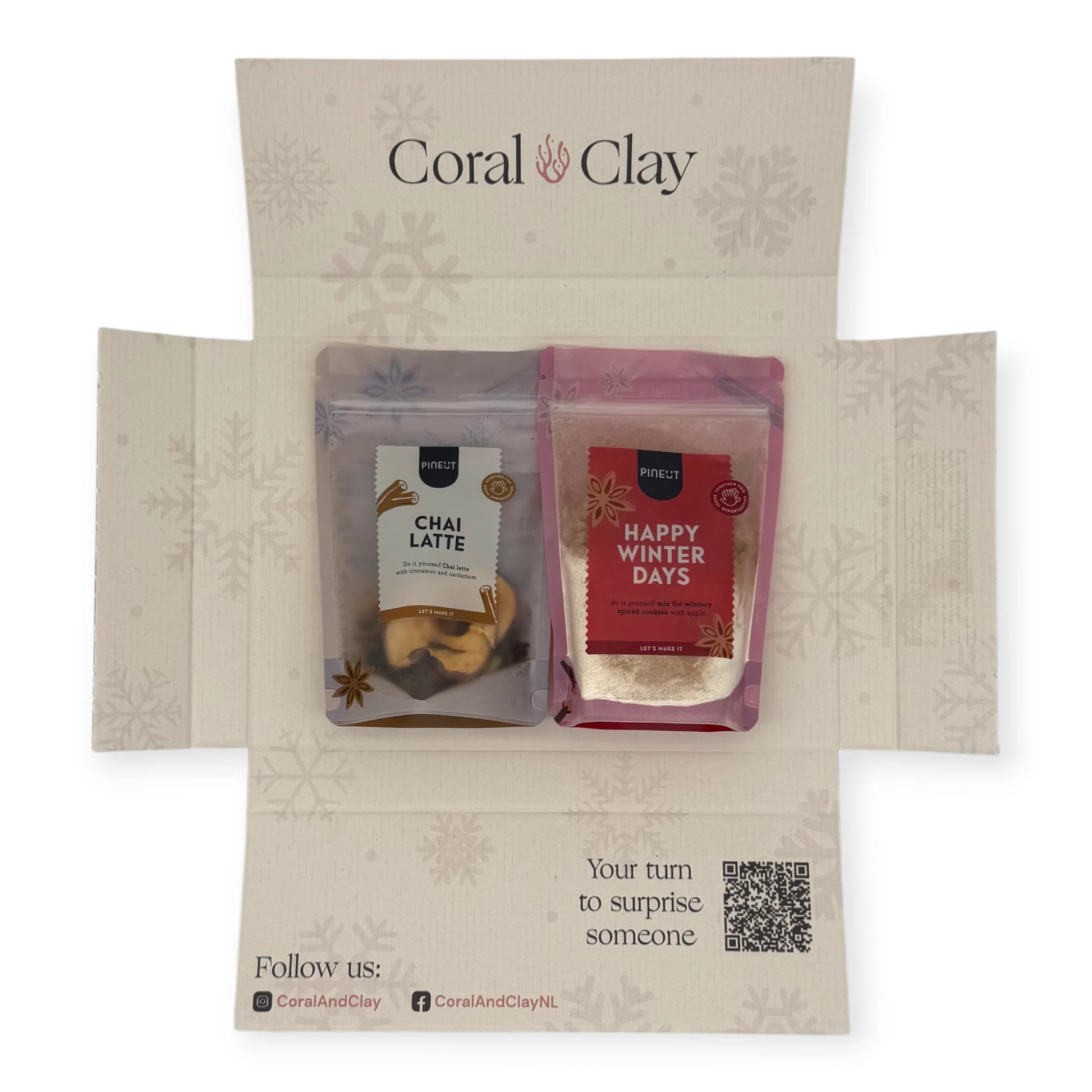 Top-down view of the Coral & Clay Chai Christmas Letterbox Gift opened to reveal Pineut Chai Latte mix and Happy Winter Days cookie mix inside the festive snowflake-printed box.